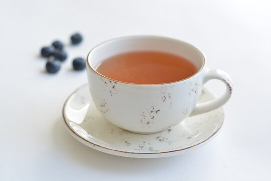 A white ceramic cup of fruit tea on white background. Copy space.