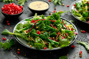 Tenderstem broccoli and egg noodles Asian style vegetarian salad with roasted pine nuts and pomegranate seeds