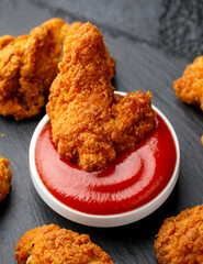 Spicy deep fried Chicken wings with ketchup on stone board