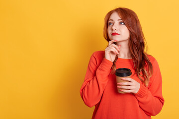 Woman thinking about future, holding disposable cup of coffee, looking aside, wearing casually, copy space for advertisement or promotional text, red haired female with pensive look.