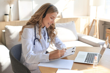 Concentrated doctor working online with a laptop sitting in a desk in a consultation.