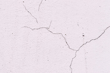 Light textured plaster as a background.Cracks in the wall