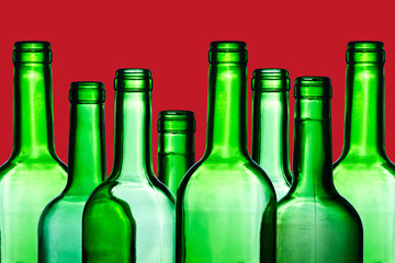 Green wine bottle. Empty glass isolated on red. Set of blank no label wine bottle in a row. Winery shelf texture. Alcohol background. Shiny transparent vibrant color panoramic view.