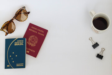 Flat lay italian and brazilian passport travel and organization concept, white background, coffee, sunglasses.