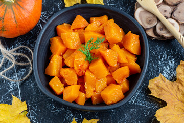 Thanksgiving roasted pumpkin in clay plate on dark background. Harvesting