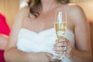Woman or bride holding a glass of wine or champagne while she gets ready for her wedding
