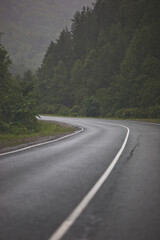 Fototapeta premium Asphalt road through the mountains forest in rainy season