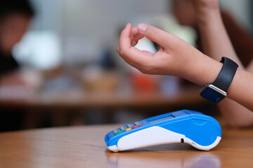 close up people using smart watch to pay over pos terminal on counter. blur background