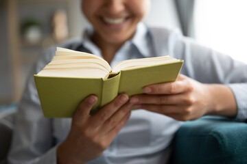 Close up selective focus on indian female hands hold read interesting book, enjoy free time on...