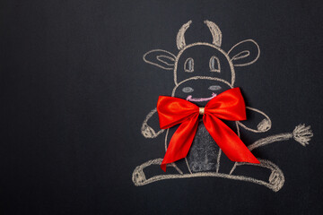 Ox with red bow symbol of new 2021 year drawn on black chalkboard. Copy space