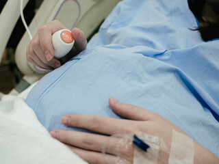 Pregnant women with big belly pressing emergency button in hospital ward for calling nurse or...