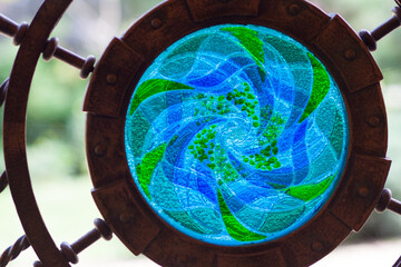 Close up of round green-blue stained glass that is part of the fence
