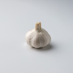 The head of garlic lies on a white-gray background.