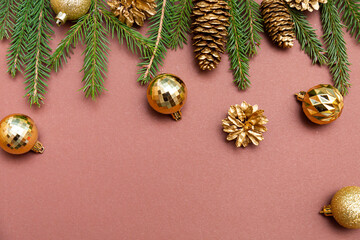 Golden Christmas balls, pine cones and fir branches on a brown background space for text. Christmas and New Years composition
