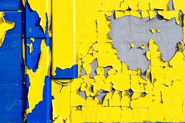 A fragment of the facade with blue spots peeking out from under peeling yellow and green paint.