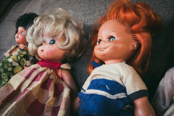 An old children's doll for girls with a gray background behind. A children's toy from the time of the communist system in Eastern Europe. Old plastic female doll. The concept of old children's toys