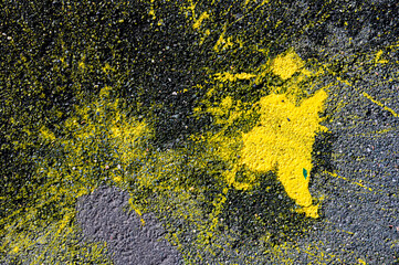 An abstract drawing formed by patches of yellow paint on cracked black asphalt.