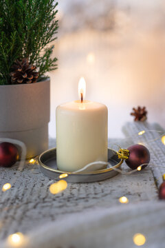 burning candle near a misted window, potted Christmas tree and Christmas decor. Holiday mood. Vertical image.