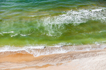 Sea, waves and surf on the sandy coast on a clear day. The view from the top.