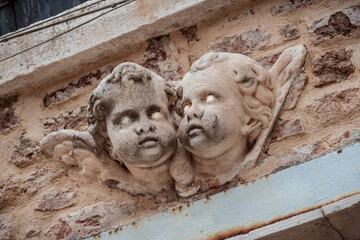 creepy childish angel faces with small wings on brick wall