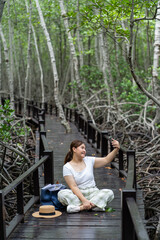 Asian women traveling nature forest and using smartphone. Walking path in the tropical jungle.
