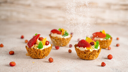 Bright background of cakes with strawberries and red top sprinkling by powdered sugar