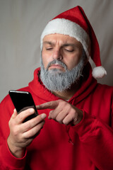 Santa Claus types something on his cell phone and looks suspicious