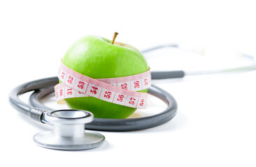 Measuring tape wrapped around a green apple with  stethoscope isolated on white