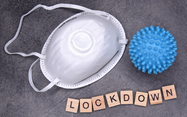 LOCKDOWN - in Großbuchstaben, FFP2-Maske und blaues Coronavirus