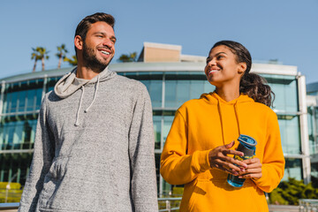 Young mixed race couple talking during jogging with modern building behind