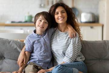 Family portrait smiling young beautiful mother and adorable son hugging, looking at camera, happy...