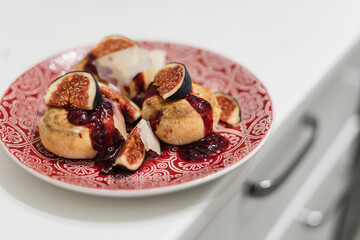 Cottage cheese pancakes with strawberry jam, figs and cheese slices in plate on table