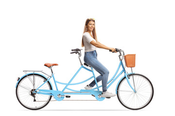 Smiling young woman in casual clothes riding a tandem bicycle