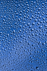Misted glass, drops close-up on a rainbow background. The image is tinted in the color of the year-classic blue.