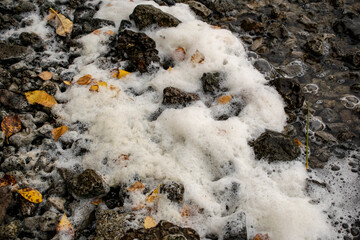Rocky sea shore covered with foam.