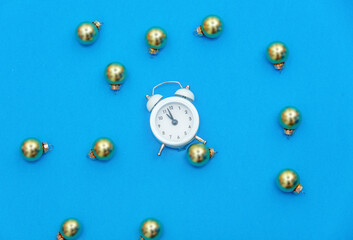 Silver baubles and alarm clock on blue background, side view