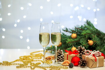 Two glasses of champagne composition with Christmas and new year decorations on a blurry background of burning garlands