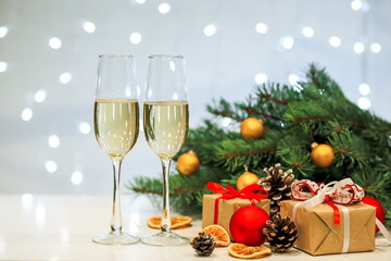 Two glasses of champagne composition with Christmas and new year decorations on a blurry background of burning garlands