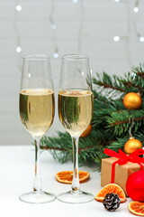 Two glasses of champagne composition with Christmas and new year decorations on a blurry background of burning garlands, vertical arrangement