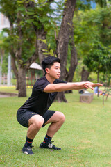 asian young man do squat  excercise alone  in park