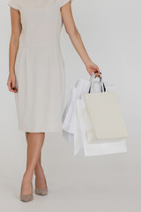 Cropped image of woman holding paper bags on white background.