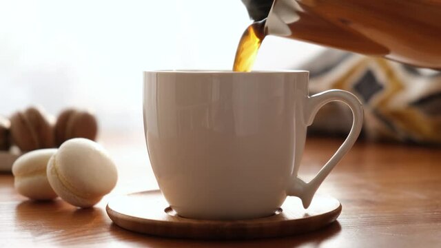 Pouring coffee in cup on a wooden table. Black coffee morning cup