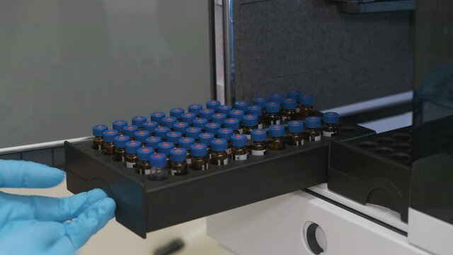 Analytical chemist puts a vials to auto sampler of HPLC system. Development pharmaceuticals and vaccine in the chemical laboratory. 