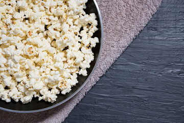 Tasty salted popcorn in pan on dark background