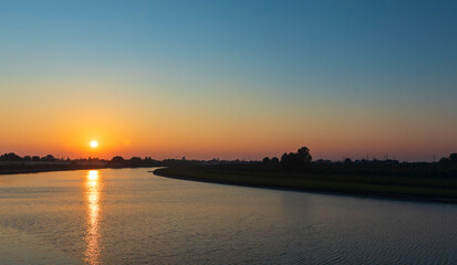Fototapeta premium The Kura river flowing through the city of Neftechala at sunset