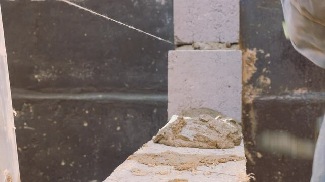 Construction work. Cinder block laying. Work of masons. Leveling the level of brickwork with a special tool.