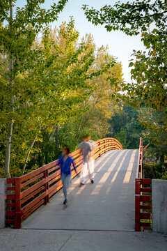 People Walking Over A Foot Bridge In A Boise Idaho City Park