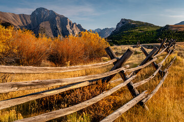 Rustic pole fence leads into the distant mountain range in autumn
