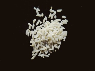 Indian white rice kept in black background. White rice is milled rice. After milling, the rice is polished, resulting in a seed with a bright, white, shiny appearance