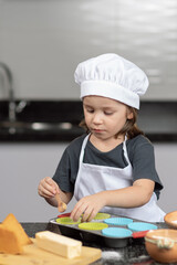 Little boy  cooking pumpkin cupcakes